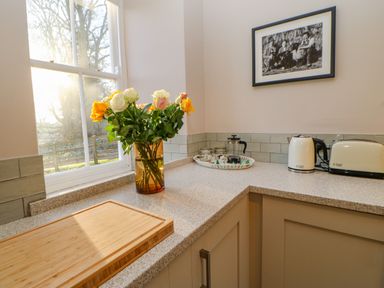 A kitchen countertop with a vase of flowers a cutting board a kettle toaster and a French press at East Farmhouse Cottage Humshaugh near Hexham