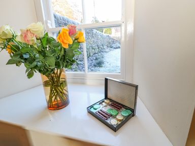 A vase with roses and a box of assorted chocolates on a windowsill at East Farmhouse Cottage in Humshaugh near Hexham
