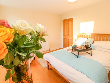 A bedroom with a wooden bed and breakfast tray on bed at East Farmhouse Cottage in Humshaugh near Hexham