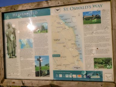 An outdoor wooden information board with a map and details about St Oswalds Way and Heavenfield near Hexham