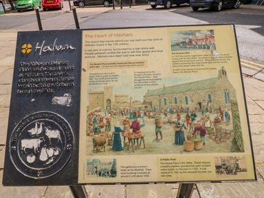 An informational sign about Hexham history with text and illustrations on a sidewalk