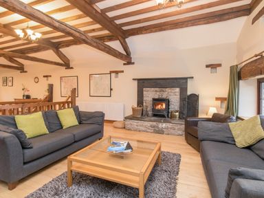 A living room with two gray sofas green cushions a wooden coffee table and a fireplace at Riven Oak in Lyth Valley near Levens
