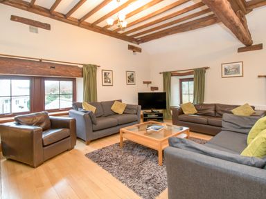 A living room with sofas armchair coffee table and television at Riven Oak in Lyth Valley near Levens