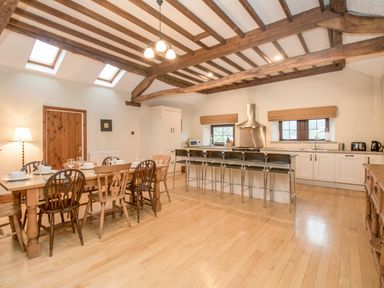 A kitchen and dining area with wooden beams a dining table and stools at Riven Oak in Lyth Valley near Levens