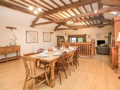 A dining room with a wooden table and chairs under exposed ceiling beams at Riven Oak in Lyth Valley near Levens