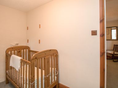 A wooden baby crib in a small room with a towel hanging on the side at Riven Oak in Lyth Valley near Levens
