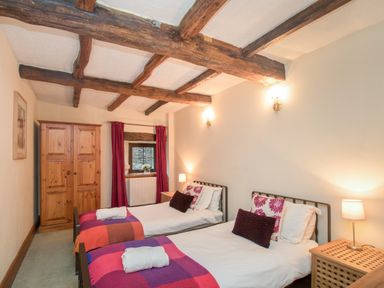 A bedroom with two single beds a wooden wardrobe and exposed wooden ceiling beams at Riven Oak in Lyth Valley near Levens