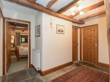 A hallway with wooden doors a radiator a framed picture and a patterned rug at Riven Oak in Lyth Valley near Levens