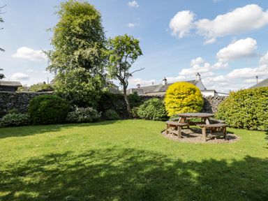 A garden with green grass bushes and a wooden picnic table at Riven Oak in Lyth Valley near Levens