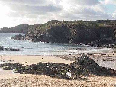 A sandy beach with rocks and cliffs by the sea at Y Barcud in Holyhead