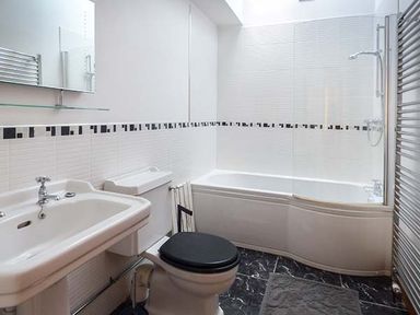 A bathroom with a sink a toilet a bathtub with shower and a towel radiator at Y Barcud in Holyhead