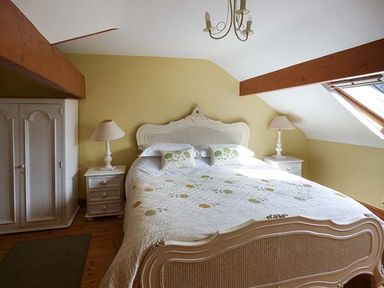 A bedroom with a double bed two bedside tables with lamps a wardrobe and a skylight window at Y Barcud in Holyhead