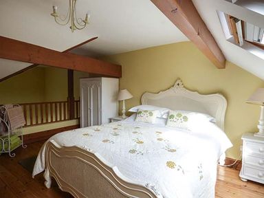 A bedroom with a bed a wardrobe two bedside tables and lamps at Y Barcud in Holyhead