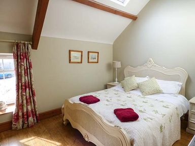 A bedroom with a double bed bedside tables lamp and floral curtains at Bran Goesgoch in Holyhead