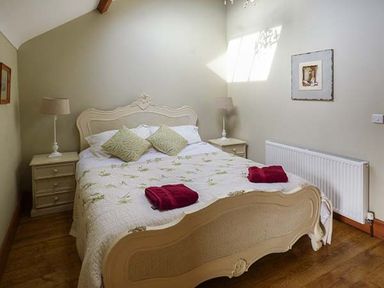 A bedroom with a double bed two bedside tables with lamps two burgundy towels and a framed picture on the wall at Bran Goesgoch in Holyhead