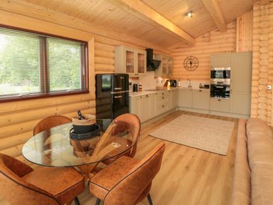 A kitchen and dining area with glass table and brown chairs in a wooden interior at Carlton Lodge 1 in Stokesley