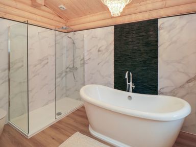 A bathroom with a freestanding bathtub and a glass shower enclosure with wood ceiling at Carlton Lodge 1 in Stokesley