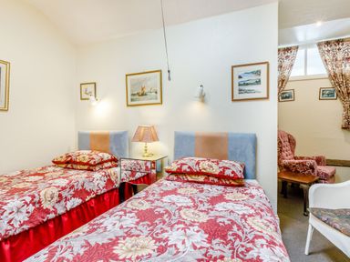 A room with two single beds with floral bedspreads and a bedside table with a lamp at Clooneavin Apartment 3 Lynmouth near Lynton