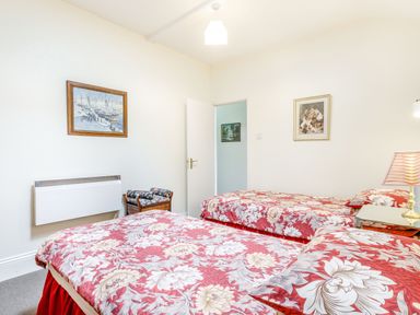 A bedroom with two single beds with floral bedspreads and paintings on the walls at Clooneavin Apartment 3 Lynmouth near Lynton