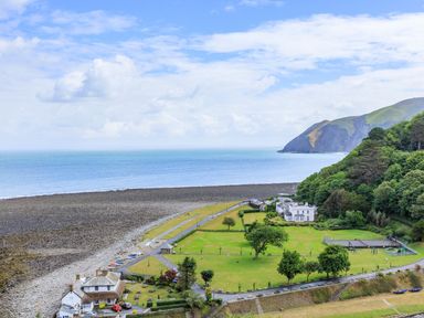 A coastal area with houses trees a grassy field and a rocky shoreline at Clooneavin Apartment 3 in Lynmouth near Lynton
