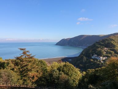 A coastal view with hills trees and houses near the sea at Clooneavin Apartment 5 Lynmouth near Lynton