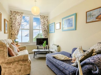 A living room with two sofas a coffee table a television and a large window with ocean view at Clooneavin Apartment 5 in Lynmouth near Lynton
