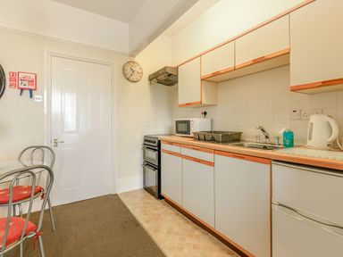 A kitchen with cabinets stove microwave sink kettle and a dining table with chairs at Clooneavin Apartment 5 Lynmouth near Lynton