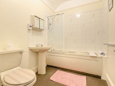 A bathroom with a toilet sink bathtub shower and pink bath mat at Clooneavin Apartment 5 Lynmouth near Lynton