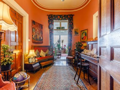 A hallway with wooden doors a patterned rug a red bench with pillows a wooden sideboard with china and two chairs at Clooneavin Apartment 8 Lynmouth near Lynton
