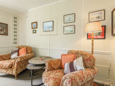 A sitting area with patterned armchairs cushions a floor lamp and framed pictures on the walls at Clooneavin Apartment 8 Lynmouth near Lynton