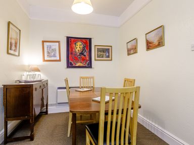 A dining room with a wooden table and chairs and framed artwork on the walls at Clooneavin Apartment 8 Lynmouth near Lynton