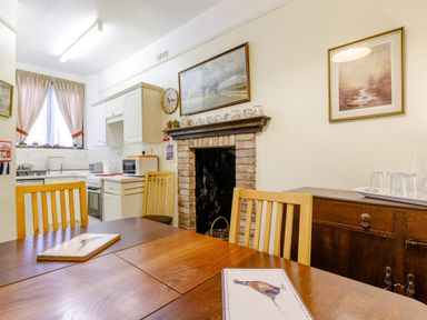A dining area with wooden chairs and table near a fireplace and kitchen at Clooneavin Apartment 8 in Lynmouth near Lynton