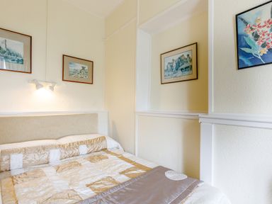 A bedroom with a bed and framed paintings on the walls at Clooneavin Apartment 8 in Lynmouth near Lynton