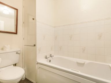 A bathroom with a toilet a bathtub a mirror and tiled walls at Clooneavin Apartment 8 in Lynmouth near Lynton