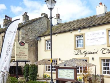 Exterior view of Bollywood Cottage Indian restaurant with outdoor seating and signage at Squirrel Lodge in Gargrave near Skipton