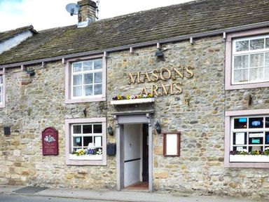 Exterior of a stone building with windows and a door with Masons Arms sign above at Squirrel Lodge in Gargrave near Skipton