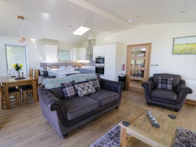 An open plan living room with sofas a wooden dining table and a kitchen at Squirrel Lodge in Gargrave near Skipton