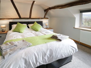 A bedroom with a bed and green cushions and throws at Bryndan in Machynlleth