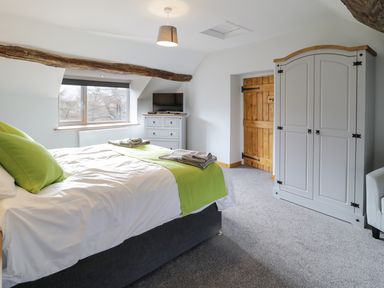 A bedroom with a bed green pillows and bed runner a wooden door and a wardrobe at Bryndan in Machynlleth