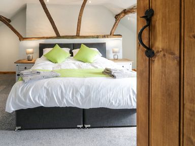 A bedroom with a double bed with green pillows and towels on the bed at Bryndan in Machynlleth