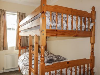 A bedroom with a wooden bunk bed and patterned curtains at 11 Pendarves in St Merryn near Padstow