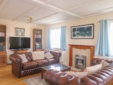 A living room with two brown leather sofas a fireplace a TV and bookshelves at 11 Pendarves St Merryn near Padstow