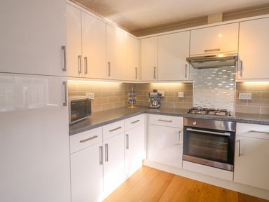 A kitchen with white cabinets a gas stove oven a microwave and a coffee machine at 11 Pendarves St Merryn near Padstow