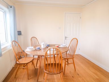 A dining room with a wooden table and four chairs set with bowls cups and a teapot at 11 Pendarves in St Merryn near Padstow