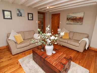 A living room with two beige sofas a wooden chest coffee table with a vase of flowers on a rug at Edendale in Longframlington near Alnwick