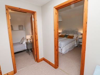 A hallway with two doorways leading to bedrooms with beds and nightstands at Edendale in Longframlington near Alnwick