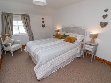 A bedroom with a bed a chair bedside tables with lamps and heart decorations on the walls at Edendale in Longframlington near Alnwick