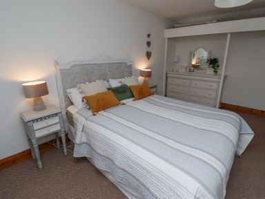 A bedroom with a bed with pillows and lamps on side tables at Edendale in Longframlington near Alnwick