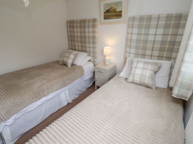 A bedroom with two single beds a nightstand with a lamp and a painting on the wall at Edendale in Longframlington near Alnwick