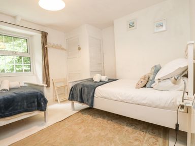 A bedroom with two single beds blue blankets and folded towels at Tinners Cottage in Liskeard